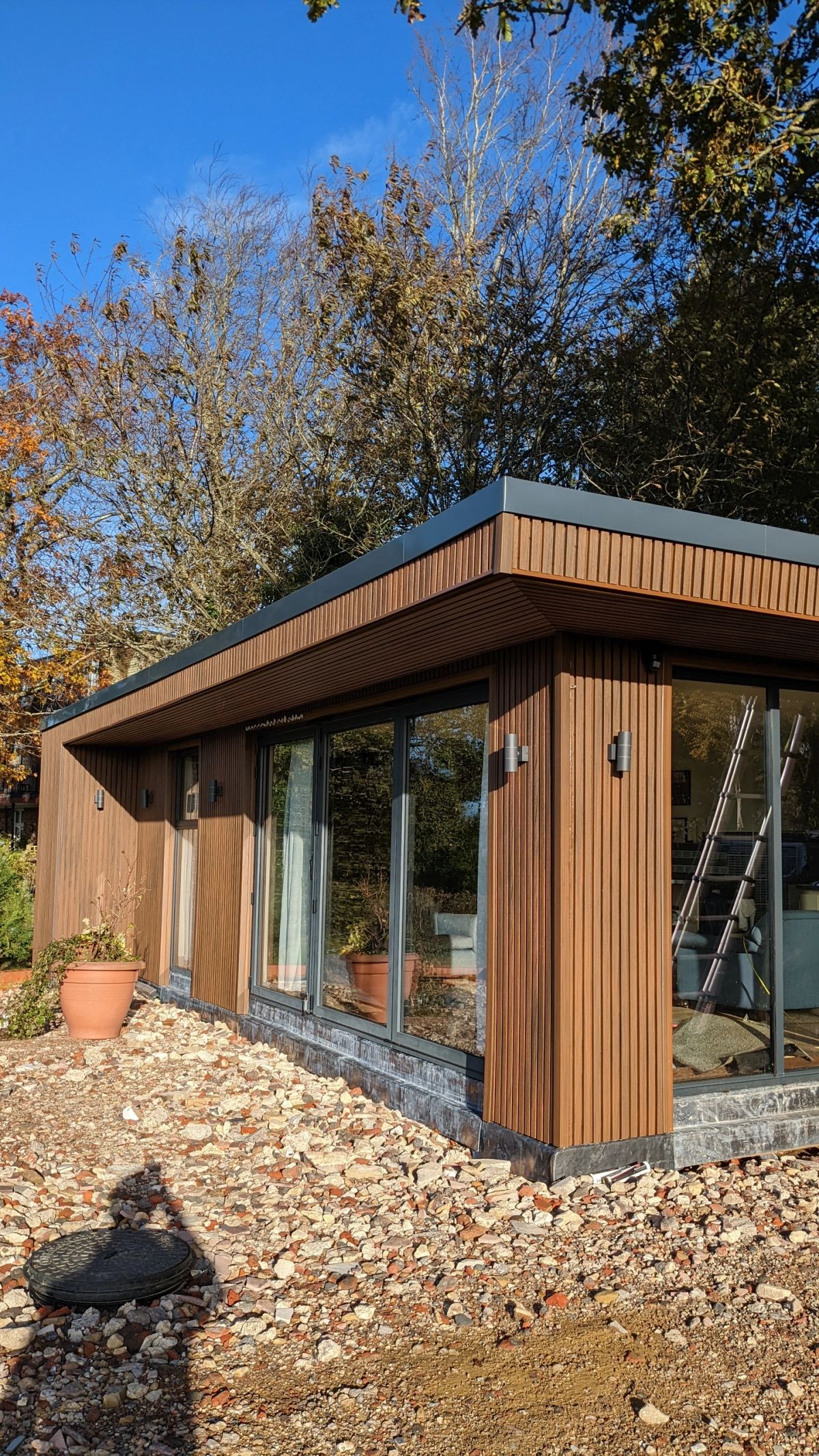 Modern garden room with large glass windows in a sunny outdoor setting