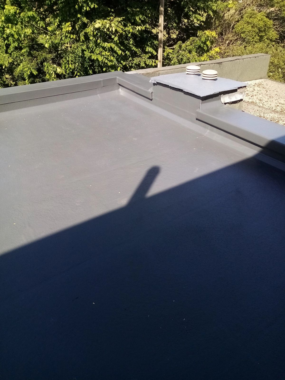 Newly installed flat roof with a ladder leaning against the house